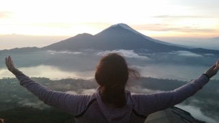 Lever de soleil sur le volcan Batur à Bali, bras grands ouverts