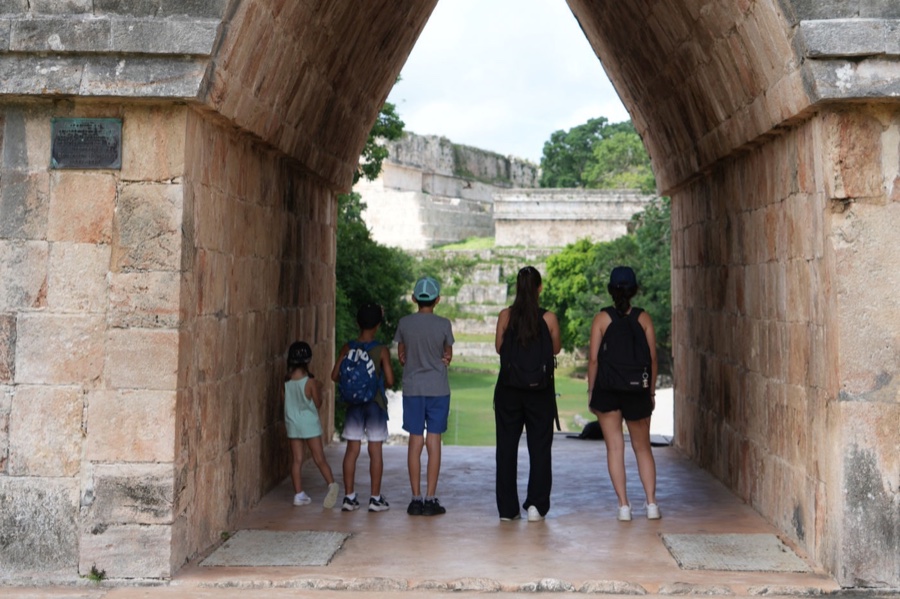 Une famille contemple des ruines mayas depuis une arche de pierre, au Mexique